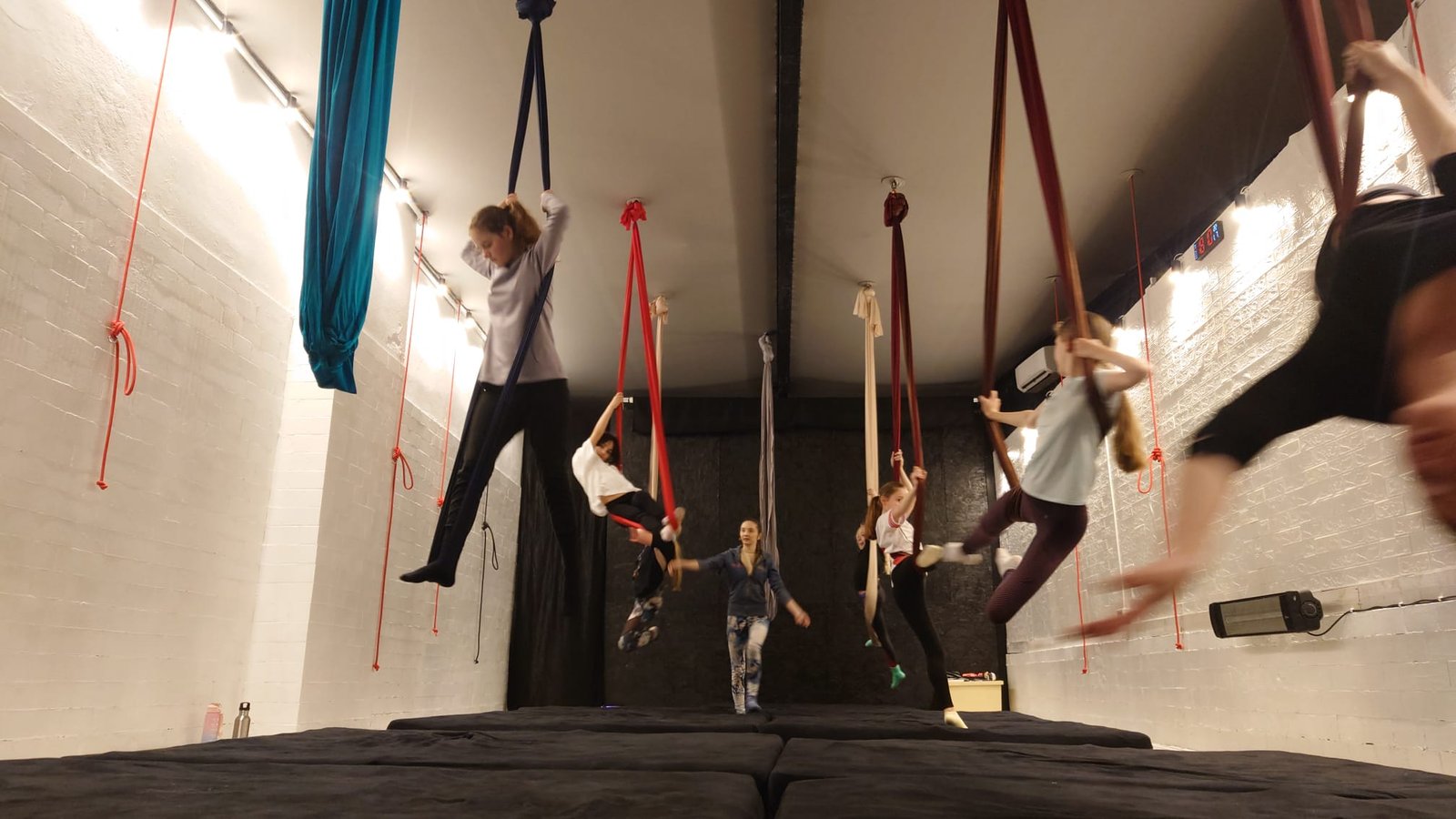 Cursante la antrenament pe eșarfe aeriene, fiecare pe aparatul ei, în studioul Aerialight